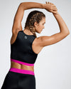 Model wearing pink and black sustainable gym crop. Rosa Nera is a longer length crop featuring a racer back and a fuchsia under bust band. Ladies Activewear made to last with premium Italian sports tech fabric created with ECONYL Regenerated Yarn.  Back view.