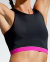 Model wearing pink and black sustainable gym crop. Rosa Nera is a longer length crop featuring a racer back and a fuchsia under bust band. Women’s Sustainable Activewear made to last with premium Italian sports tech fabric created with ECONYL Regenerated Yarn.  Close up of pink band.