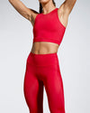 Model wearing Scultura Activewear. Red sustainable Debutto Gym crop in sporting red. Racer back crop design with high scoop neckline. Made with super soft premium sports wear fabric created from ECONYL® regenerated yarn. Hand made in our ethically compliant factory in London. Made in the UK.  Front view