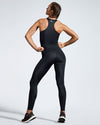 Woman wearing sustainable gym clothes. Black Energia racer back top and black Debutto sustainable gym leggings. Sustainable Gym wear made with premium sports tech fabric created with ECONYL Regenerated Yarn. Designed and made in UK. Full length Image of back.