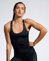Front view of women wearing a black sustainable gym top featuring a classic scoop neck and racer back. Sustainable activewear made with recovered fishing nets. Waste to Wear. Premium Gym Wear Created with ECONYL Regenerated Nylon. Designed and Made in London. 