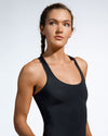 Front view of women wearing a black sustainable gym top featuring a classic scoop neck and racer back. Sustainable activewear made with recovered fishing nets. Waste to Wear. Premium Gym Wear Created with ECONYL Regenerated Nylon. Designed and Made in London. 