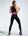 Model wearing pink and black sustainable gym leggings. Rosa Nera features a colour pop fuchsia waist band. Women’s Sustainable Gym Wear made to last with premium Italian sports tech fabric created with ECONYL Regenerated Yarn.  Back view.