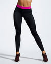 Model wearing pink and black sustainable gym leggings. Rosa Nera features a colour pop fuchsia waist band. Women’s Sustainable Activewear made to last with premium Italian sports tech fabric created with ECONYL Regenerated Yarn.  Close up of pink waistband. Front view.