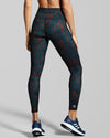 New Horizons Sienna Gym Leggings Print. Rear view of dark blue and burnt orange sienna print workout leggings. Made of recycled fabric created with yarn from pre and post consumer materials such as plastic bottles.